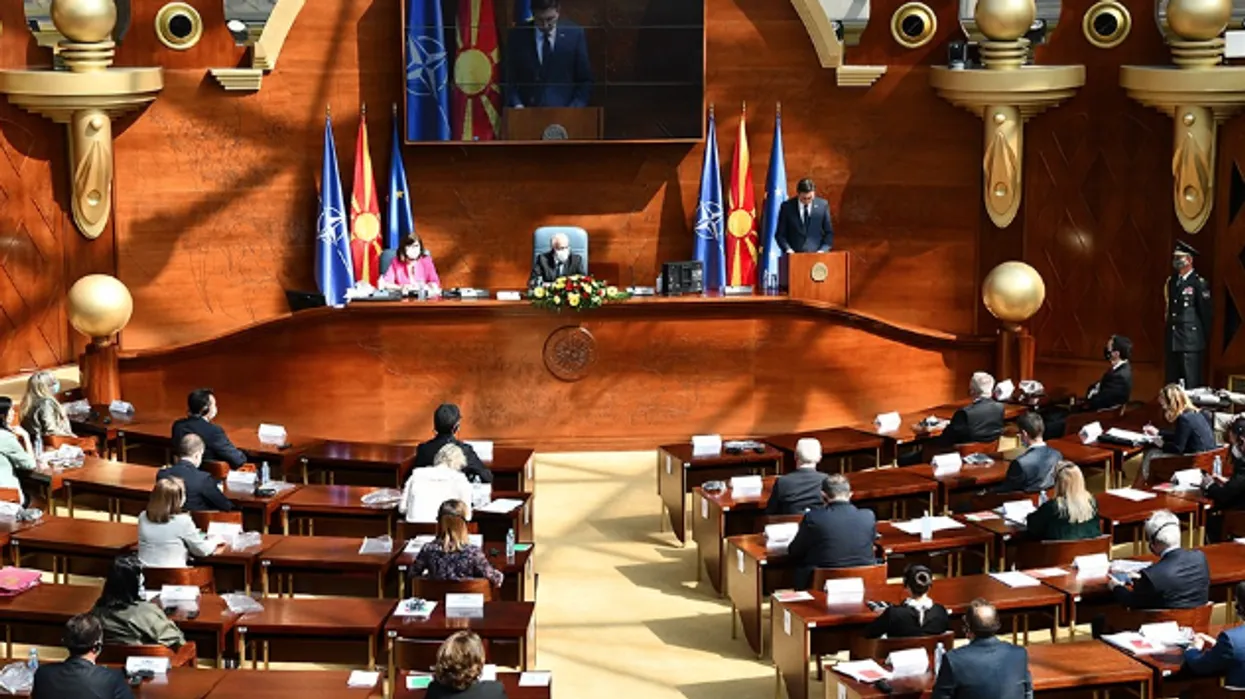 The North Macedonian Parliament (Sobranie) in session with members seated and flags of North Macedonia, EU, and NATO visible